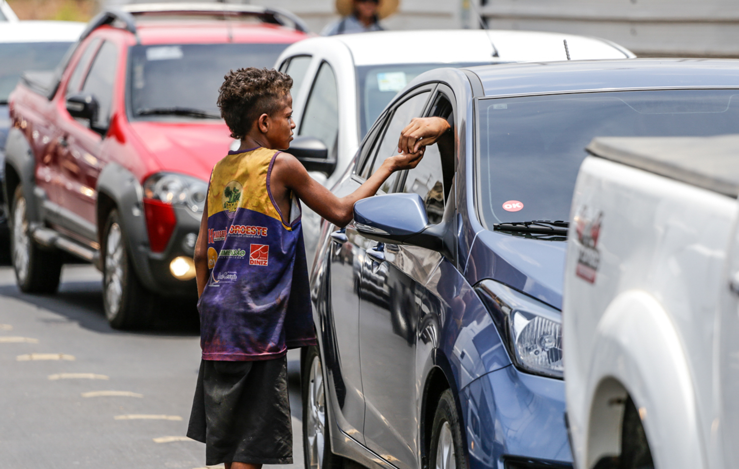 Criança de rua pedindo esmola no sinal 