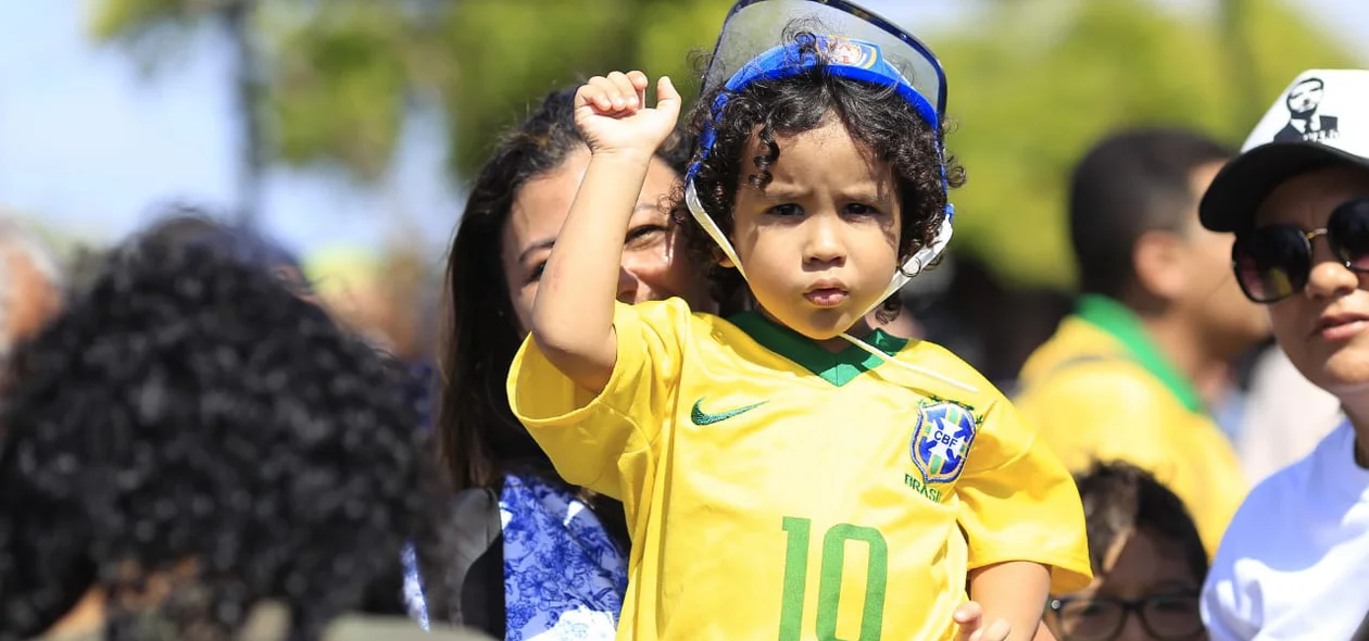 Criança vestida com a camisa do Brasil espera a chegada de Bolsonaro a Parnaíba