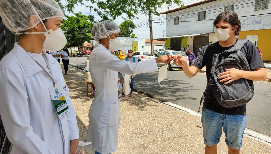Estudante recebe máscara de proteção antes de entrar no local de prova do Enem