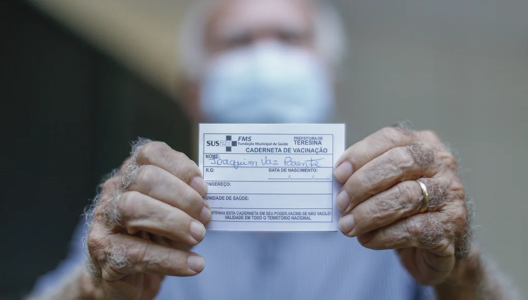 Joaquim Vaz Parente mostrando seu cartão de vacina