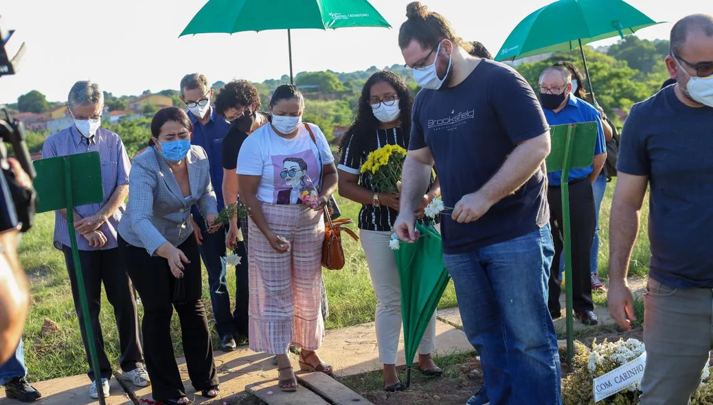 Amigos e familiares jogam flores no caixão