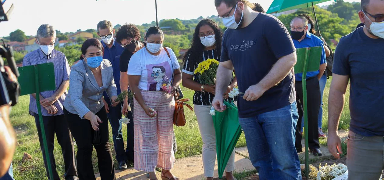 Amigos e familiares jogam flores no caixão