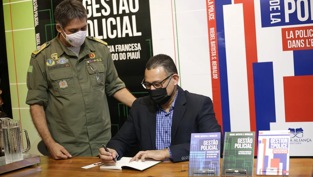 Delegado autografando livro para o comandante da polícia
