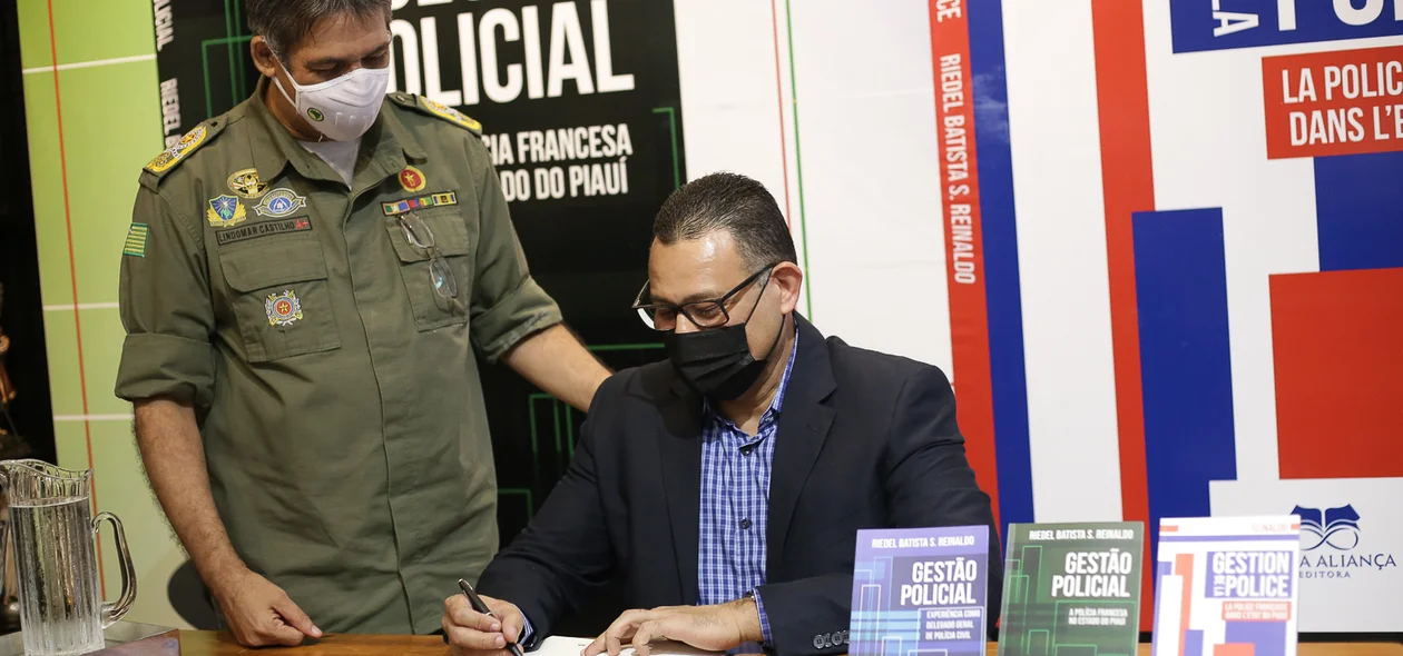 Delegado autografando livro para o comandante da polícia