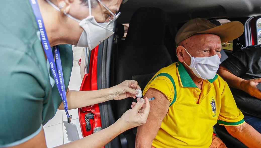 Idoso com camisa do Brasil sendo vacinado contra covid-19