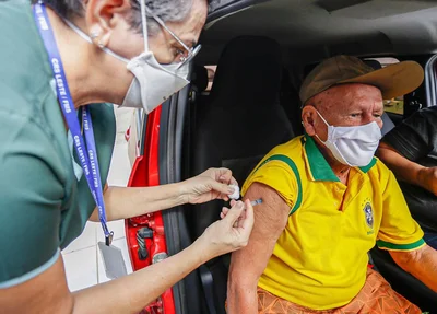Idoso com camisa do Brasil sendo vacinado contra covid-19