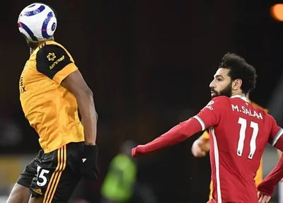 A bola esconde Willy Boly, do Wolverhampton, em disputa com Salah, do Liverpool