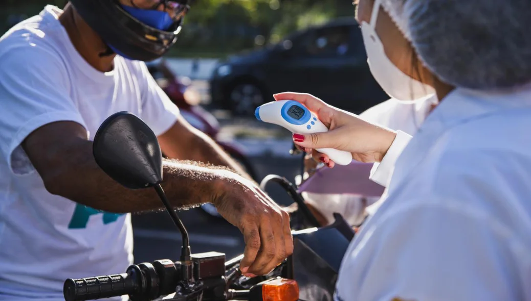 Equipe de Saúde aferindo a temperatura do  motoqueiro que passava pelo local