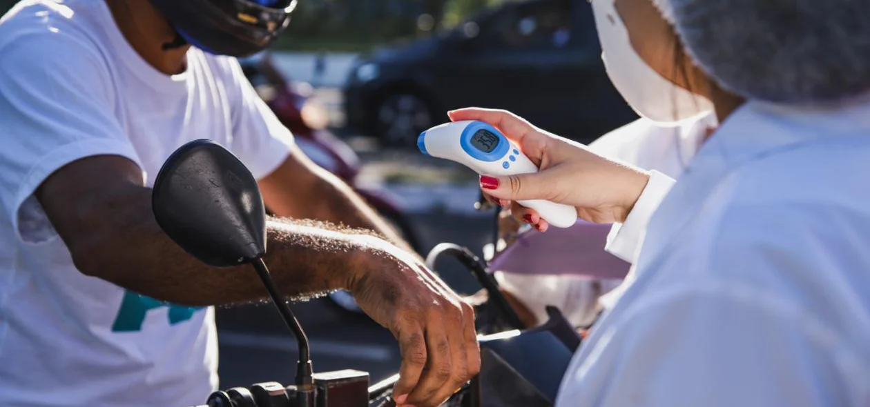 Equipe de Saúde aferindo a temperatura do  motoqueiro que passava pelo local
