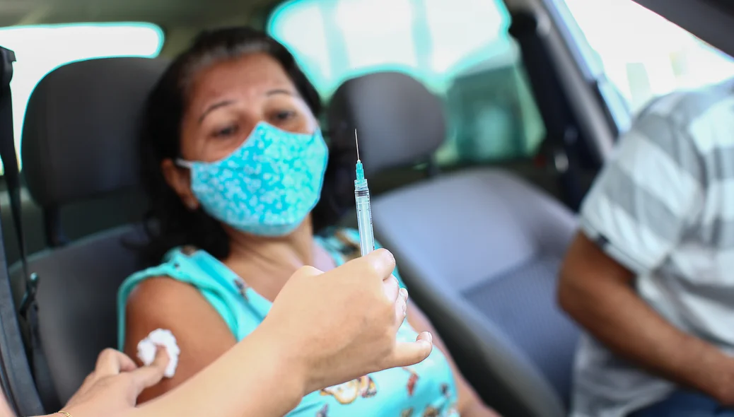 Senhora toma sua primeira dose da vacina
