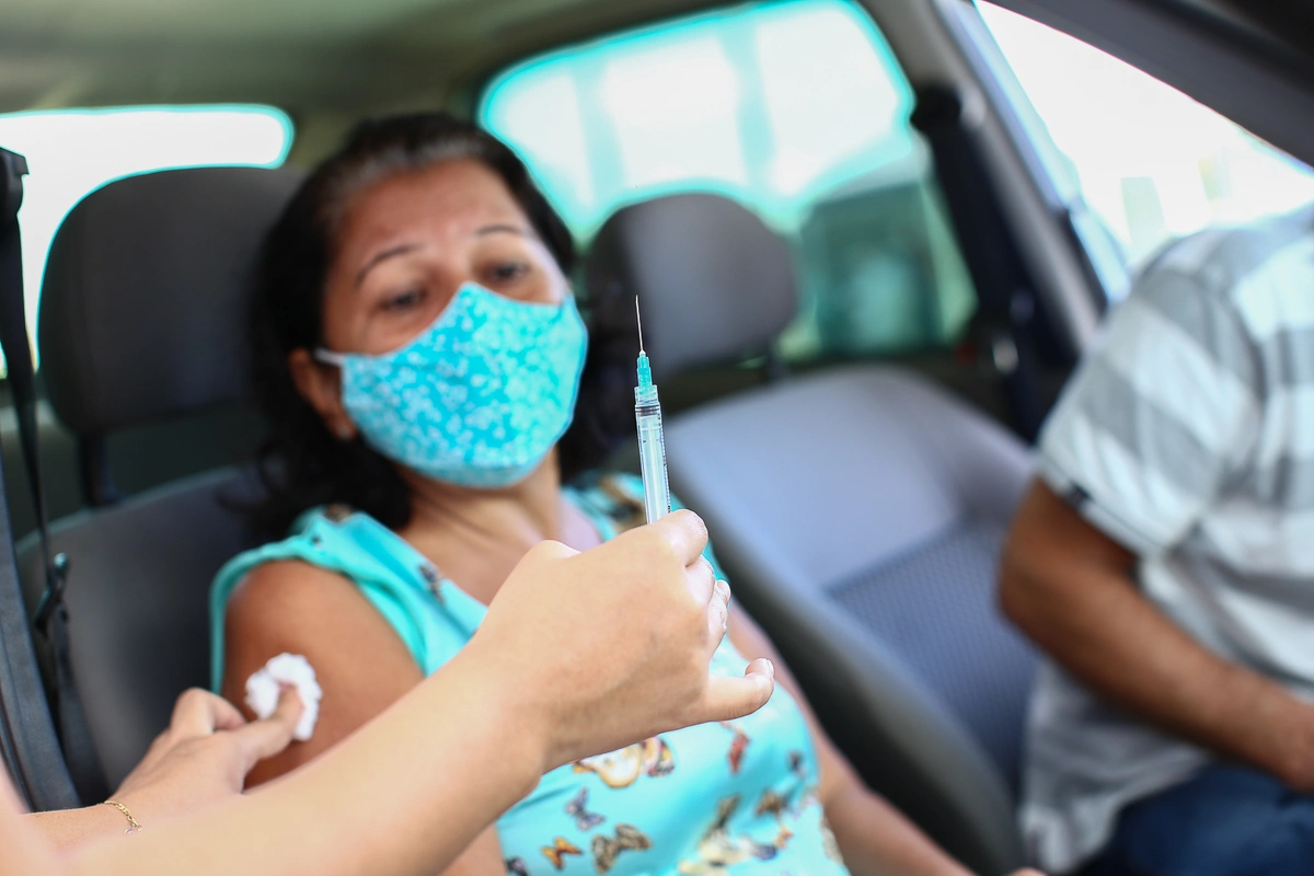 Senhora toma sua primeira dose da vacina