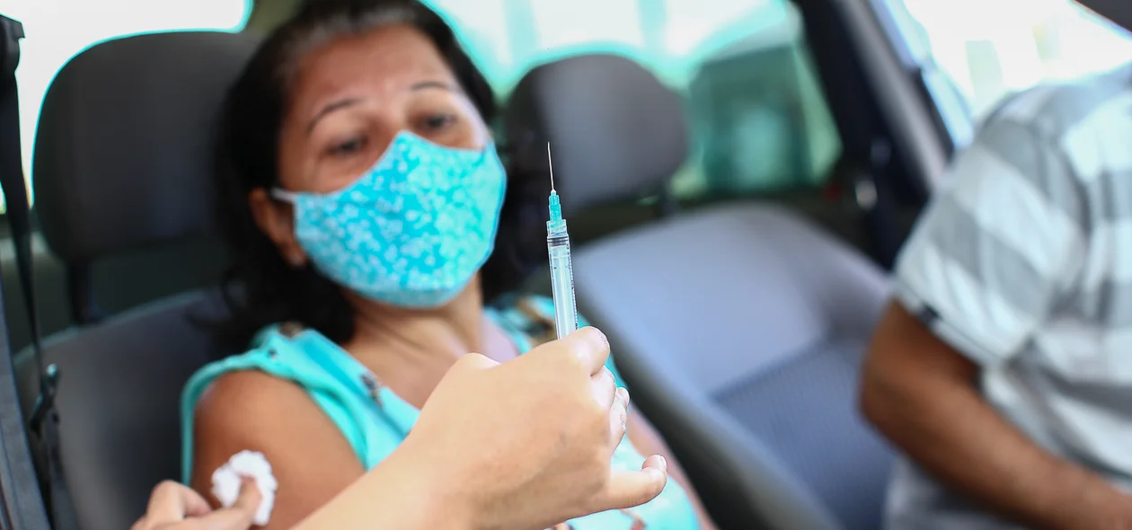 Senhora toma sua primeira dose da vacina