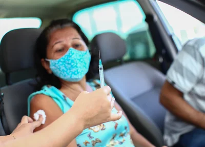 Senhora toma sua primeira dose da vacina