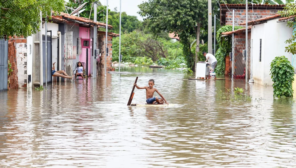 Criança improvisa balsa para se deslocar devido a quantidade de água no local