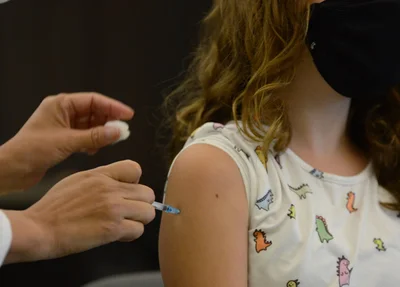 Criança sendo vacinada contra a covid-19