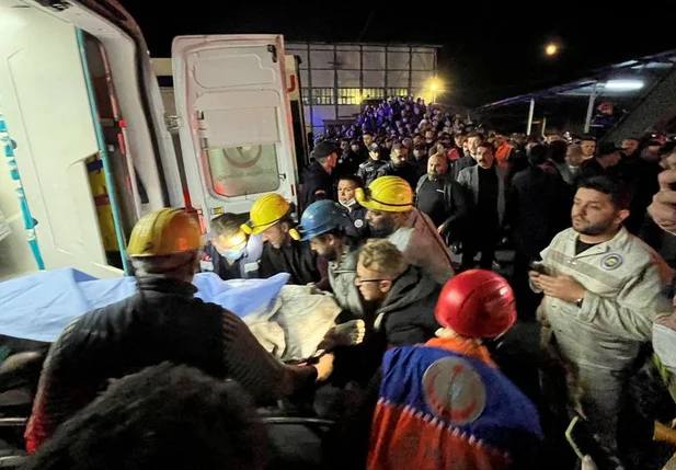 Mineiro é carregado para uma ambulância após uma mina explodir
