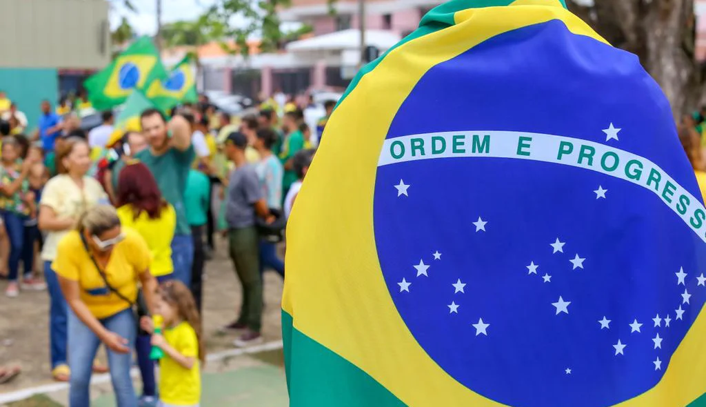 Eleitor de Jair Bolsonaro enrolado com a bandeiras do Brasil