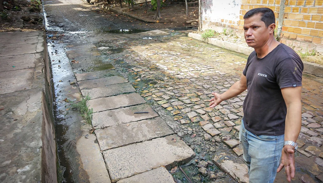 Edilson mostra água do esgoto do condomínio que está passando por cima da Rua Boa Esperança
