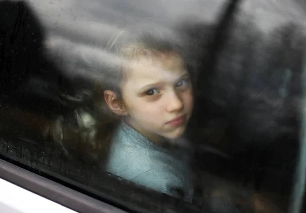 Criança ucraniana olha pela janela de um carro preso no trânsito, enquanto sua família dirige em direção à fronteira Medyka-Shehyni, entre Ucrânia e Polônia, para fugir da guerra