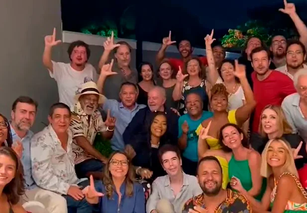 Artistas fazem a letra "L" com as mãos ao redor do ex-presidente Lula