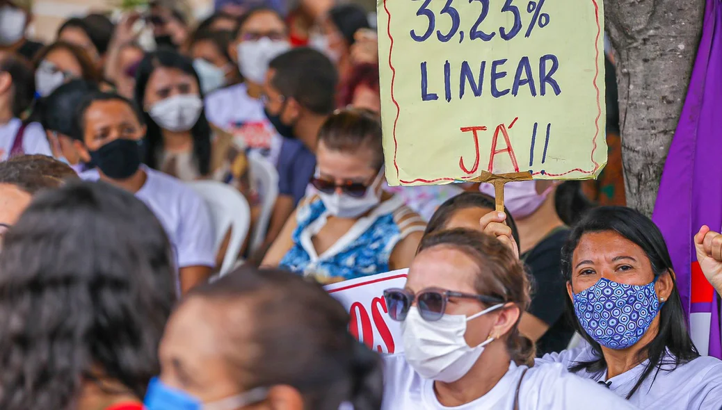 Professora com cartaz reivindicando por melhorias