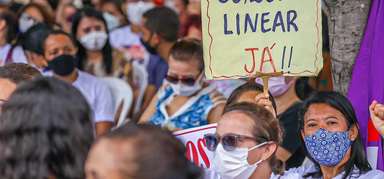 Professora com cartaz reivindicando por melhorias