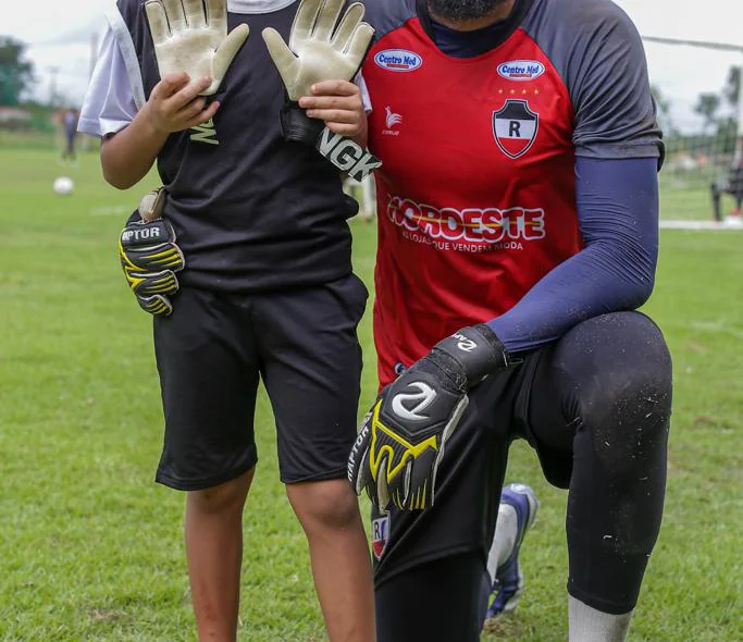 Yan mostra as luvas de goleiro junto com o pai