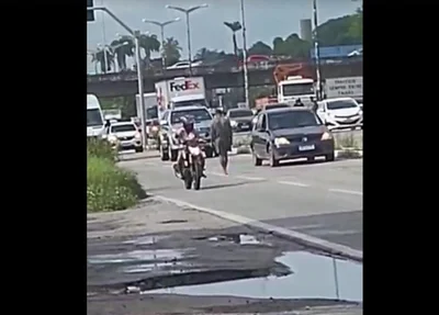 Criminoso caminhando entre os carros antes do crime