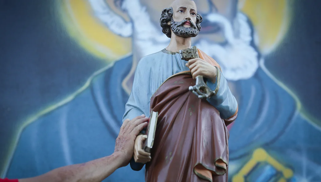 Fiel colocando a mão no santo