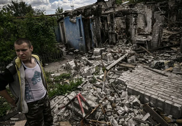 Jovem diante das ruínas de sua casa, destruída por bombardeio russo em Lisichansk.