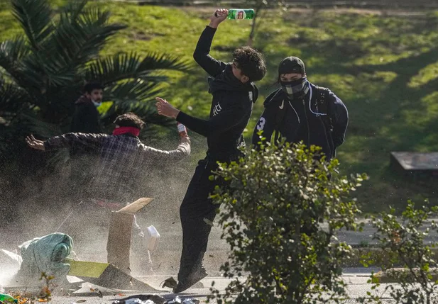 Manifestantes jogam garrafas de vidro em um canhão de água da polícia a poucos quarteirões do palácio presidencial La Moneda em Santiago, Chile