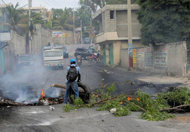 Um homem segura um pneu em rua bloqueada durante protesto contra a escassez de combustível durante o surto de violência provocado por gangues em Porto Príncipe.