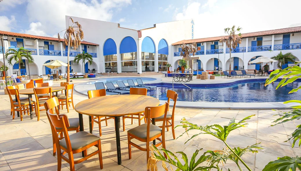 Espaço com mesas ao lado da piscina