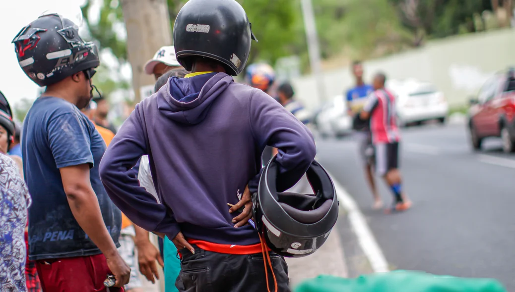 Motociclistas olhando para o corpo da vítima