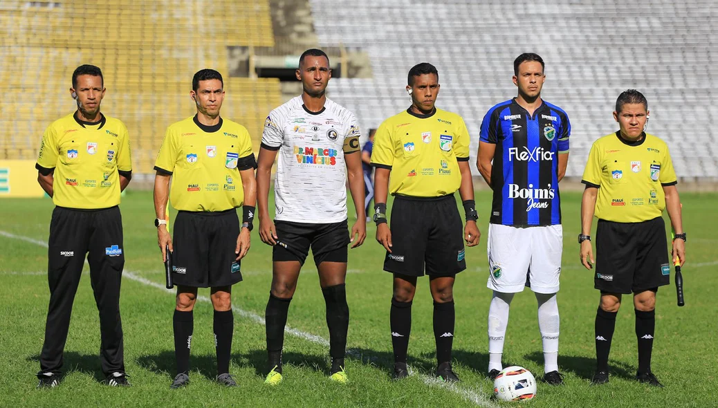 Equipe de arbitragem alinhada junto aos capitães dos times