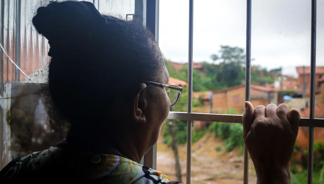 Dona Joana mostra visão para o grotão, da janela de casa
