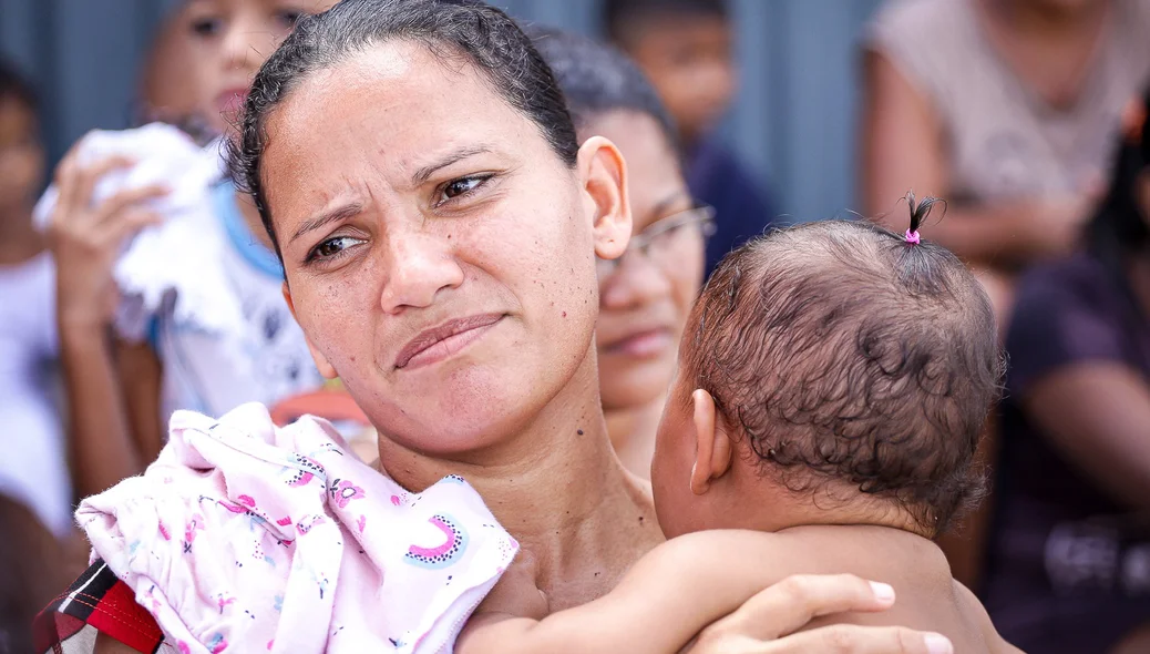 Mãe leva filho a pé com bebê no colo