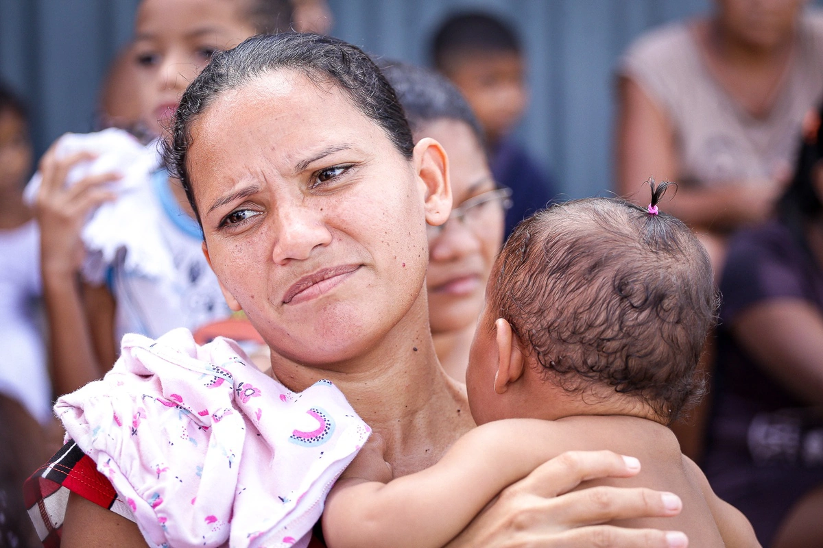Mãe leva filho a pé com bebê no colo