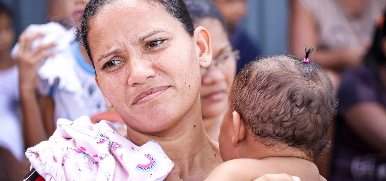 Mãe leva filho a pé com bebê no colo
