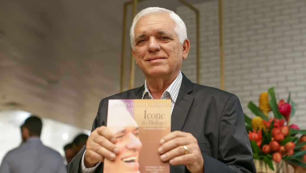 Themístocles Filho segurando um exemplar do livro