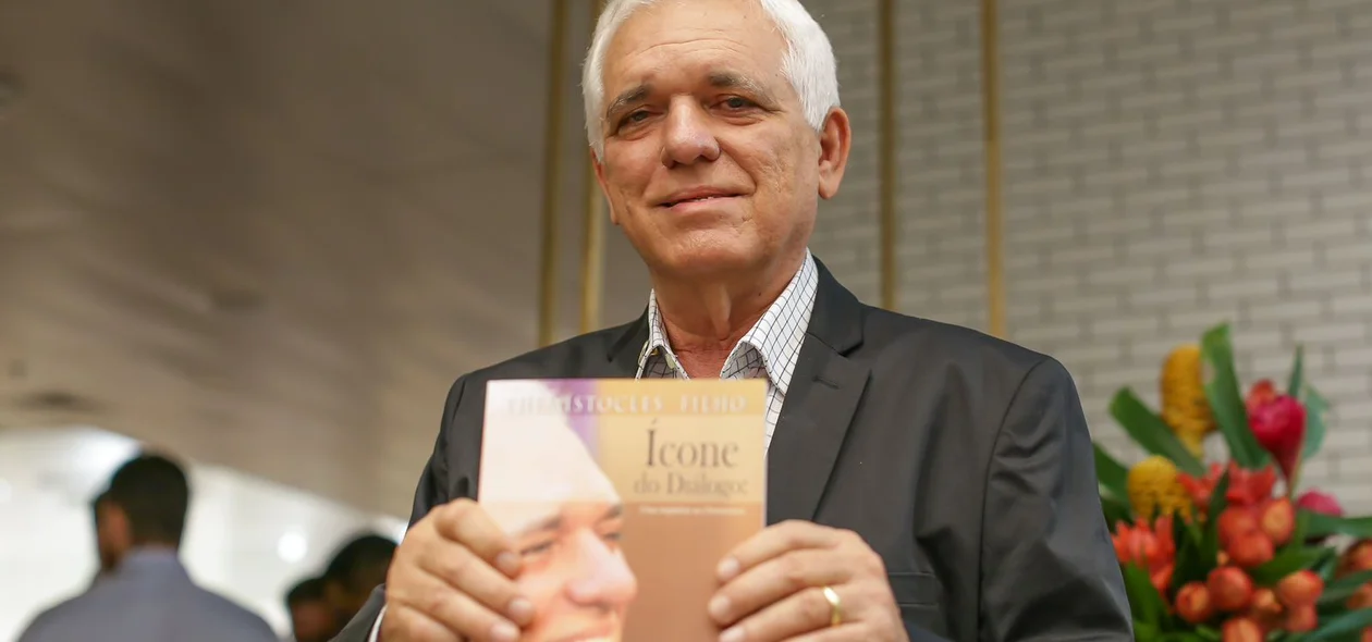 Themístocles Filho segurando um exemplar do livro