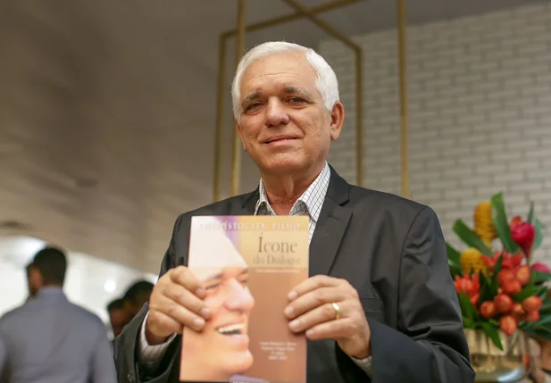 Themístocles Filho segurando um exemplar do livro