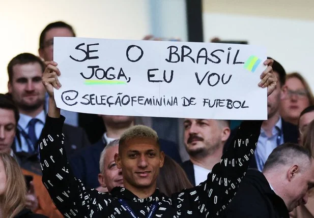 Richarlison com o cartaz de apoio à seleção brasileira de futebol feminino