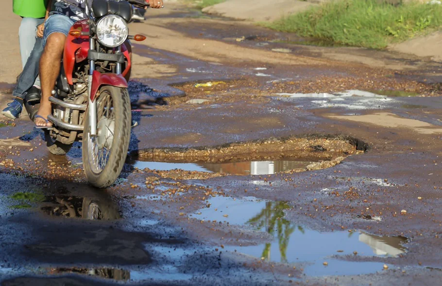 Motociclista desviando dos buracos na rua
