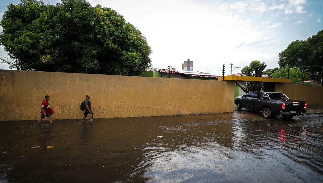Pedestres caminhando em rua alagada