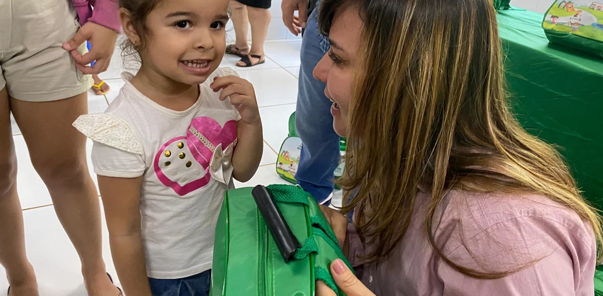 Criança recebendo o kit escolar