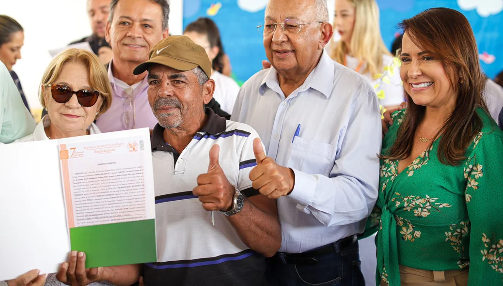 Dr. Pessoa ao lado de Ana Célia entregando documentos de regularização de imóveis