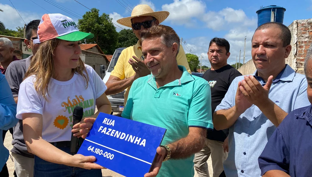 Prefeita entregando a placa da rua para um dos moradores