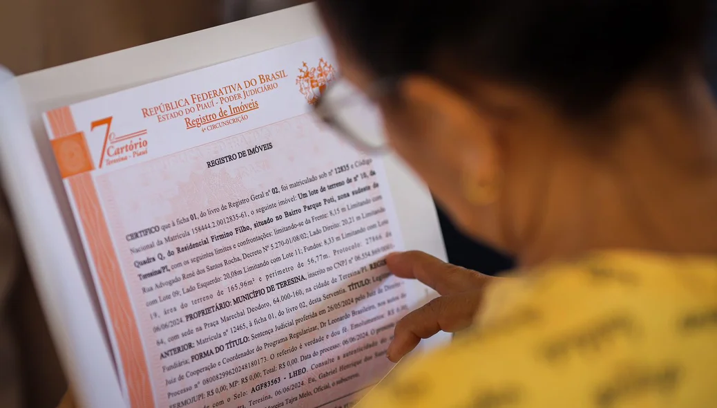 Senhora lendo o documento de regularização de seu imóvel