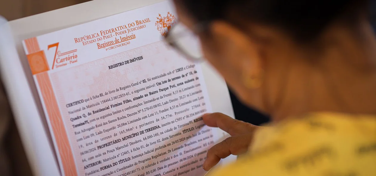 Senhora lendo o documento de regularização de seu imóvel